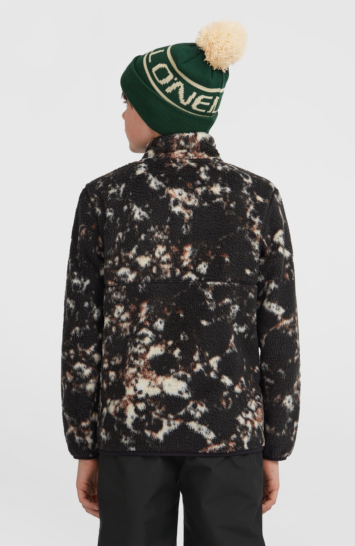 Flauschige Fleecejacke für Jungen, schwarz mit Allover-Muster in Beige, Rückansicht getragen am Model