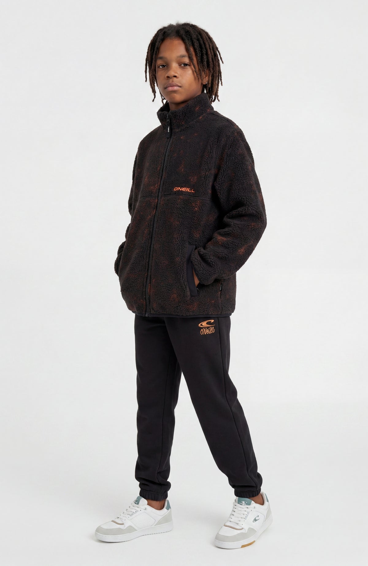 Flauschige Fleecejacke für Jungen, schwarz mit Batikmuster in Orange, getragen am Model in Ganzkörperansicht