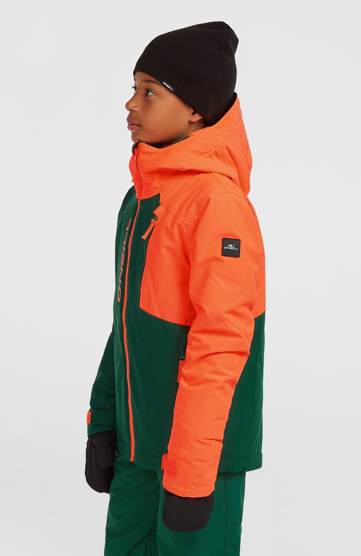 FWC'Cruz Block Skijacke für Jungen in Rot-Mix, Seitenansicht am Model mit Reißverschlusstasche und Logo-Patch am Ärmel