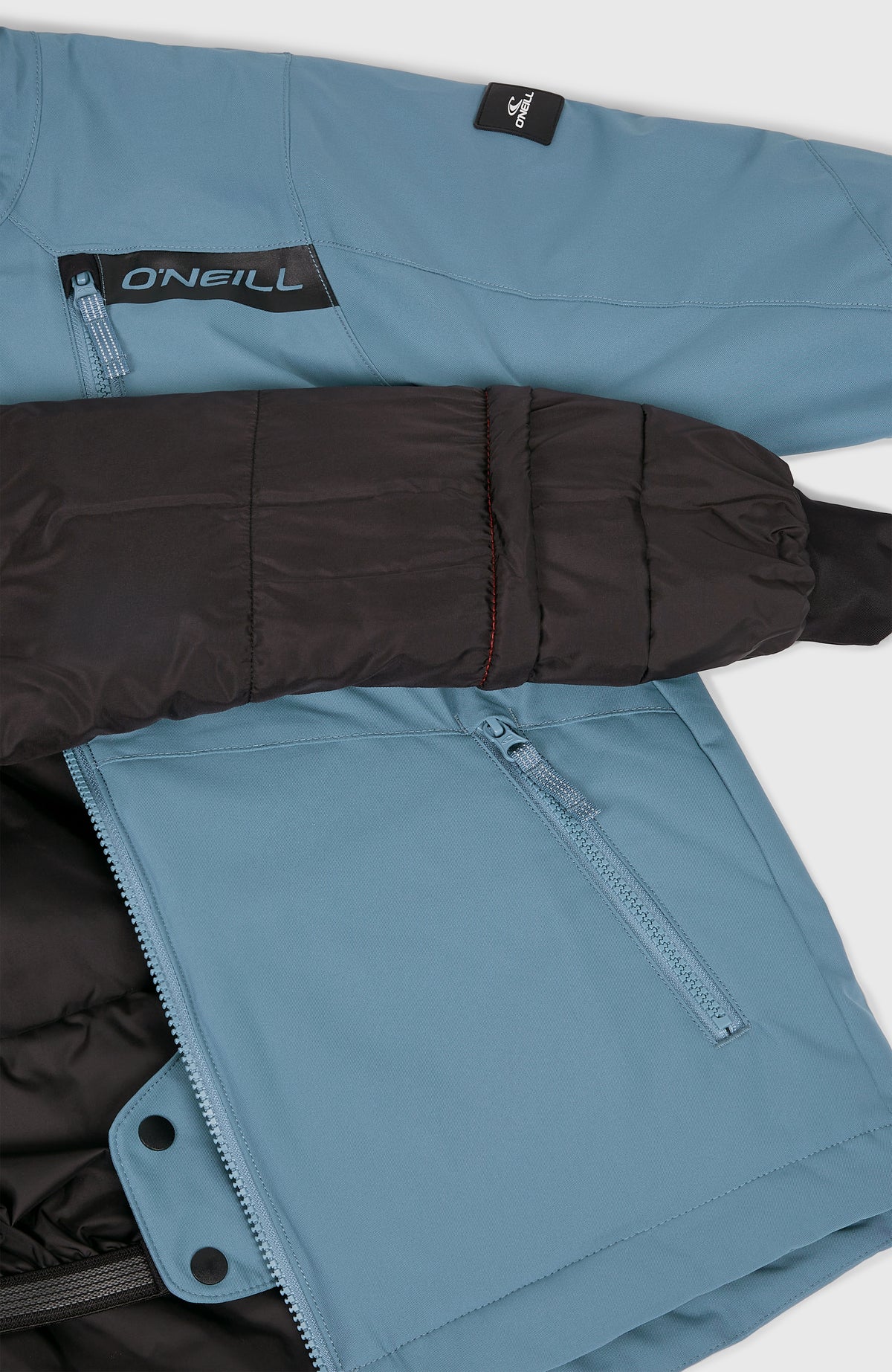 Nahaufnahme der blauen FWC'Cruz Skijacke mit sichtbarem dunklem Innenfutter, Schneefang und Reißverschlusstasche