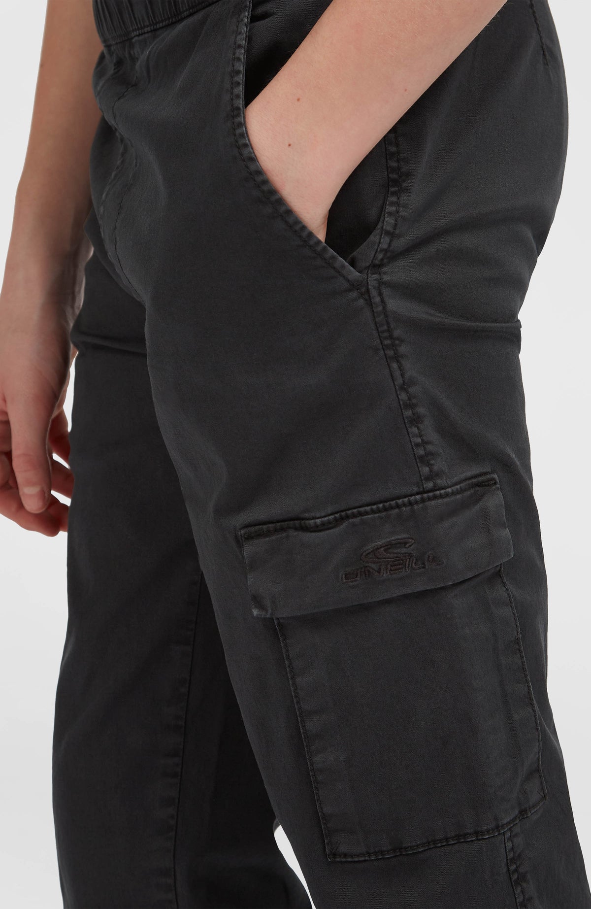 Schwarze Cargohose für Jungen, Nahaufnahme der Beintasche mit Logo-Stickerei am Model