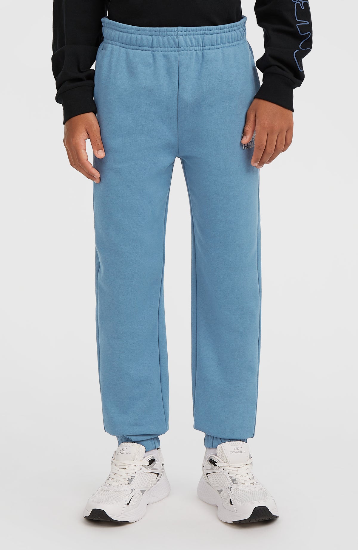 Essentials Jogginghose für Jungen, blau, Frontansicht am Model mit elastischen Bündchen am Saum
