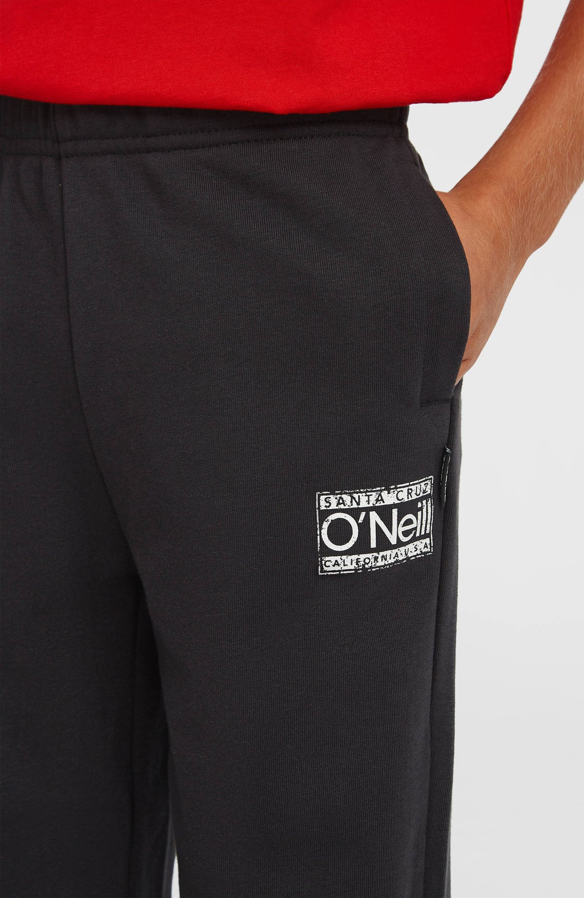 Cali Jogginghose für Jungen, schwarz, Nahaufnahme der Seitentasche und des weißen Logo-Prints am Model