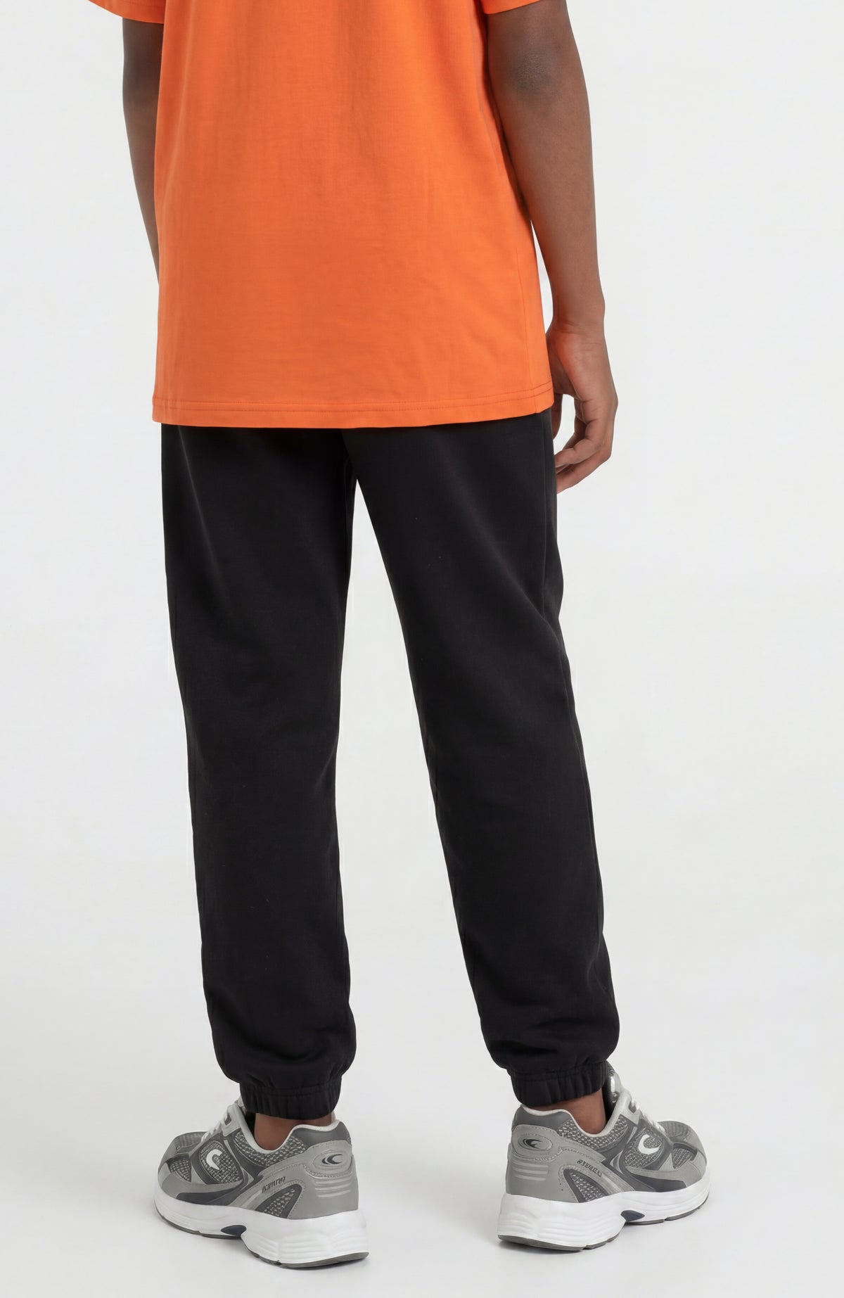 Schwarze Essentials Jogginghose für Jungen, getragen am Model, Rückansicht mit elastischen Bündchen am Saum