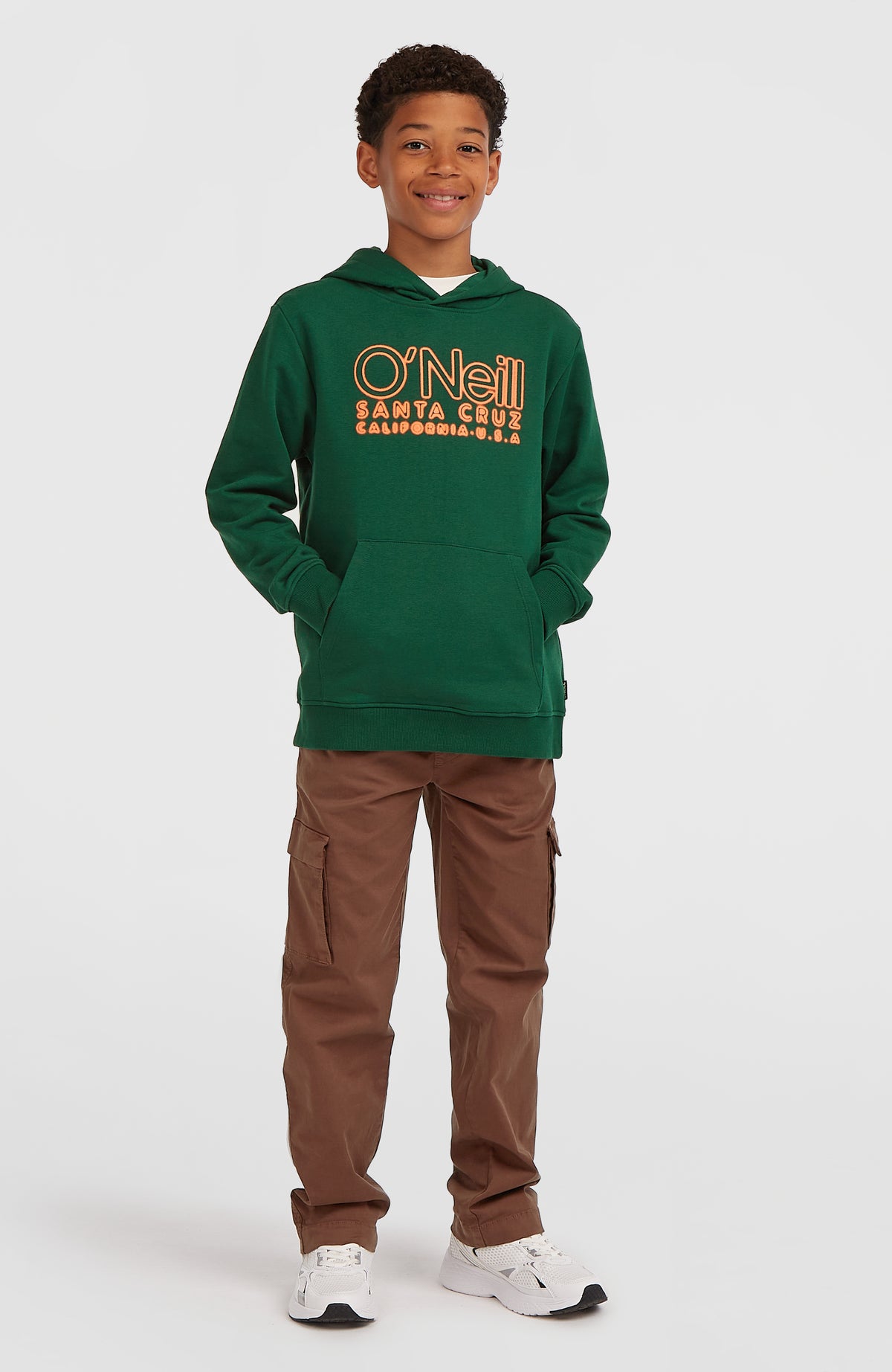 Essentials Hoodie für Jungen, grün mit Logo-Print in Orange, Ganzkörperansicht mit Kängurutasche am Model