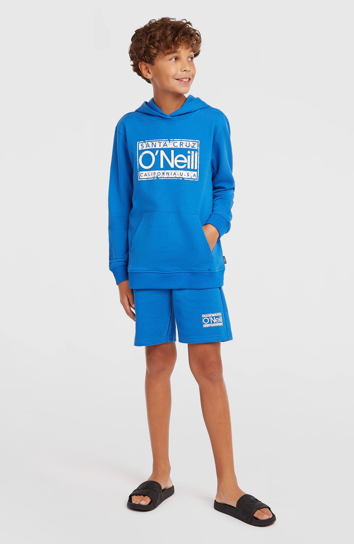 Cali Hoodie für Jungen, blau mit Logo-Print in Weiß, Ganzkörperansicht am Model, seitlich gedreht