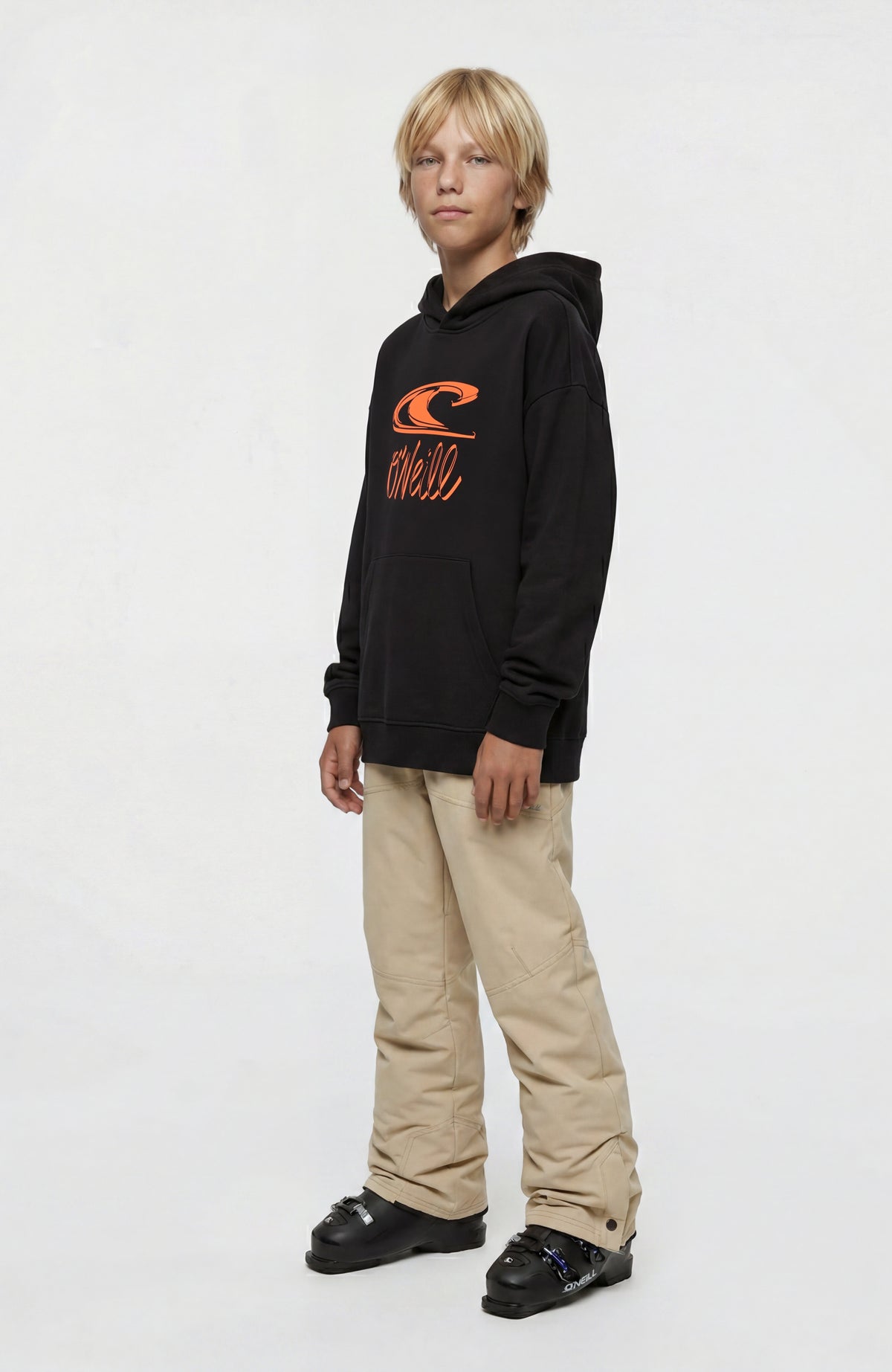 Essentials Hoodie für Jungen, schwarz mit Logo-Print in Orange, Ganzkörperansicht von der Seite getragen am Model