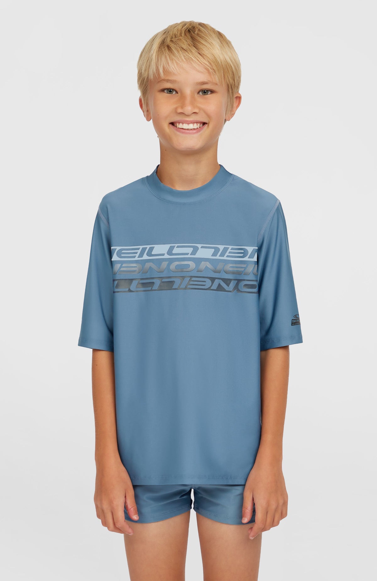 O'Neill Shortsleeve-Schwimmshirt für Jungen, blau mit Logo-Print in Hellblau und Dunkelgrau, Vorderansicht am Model