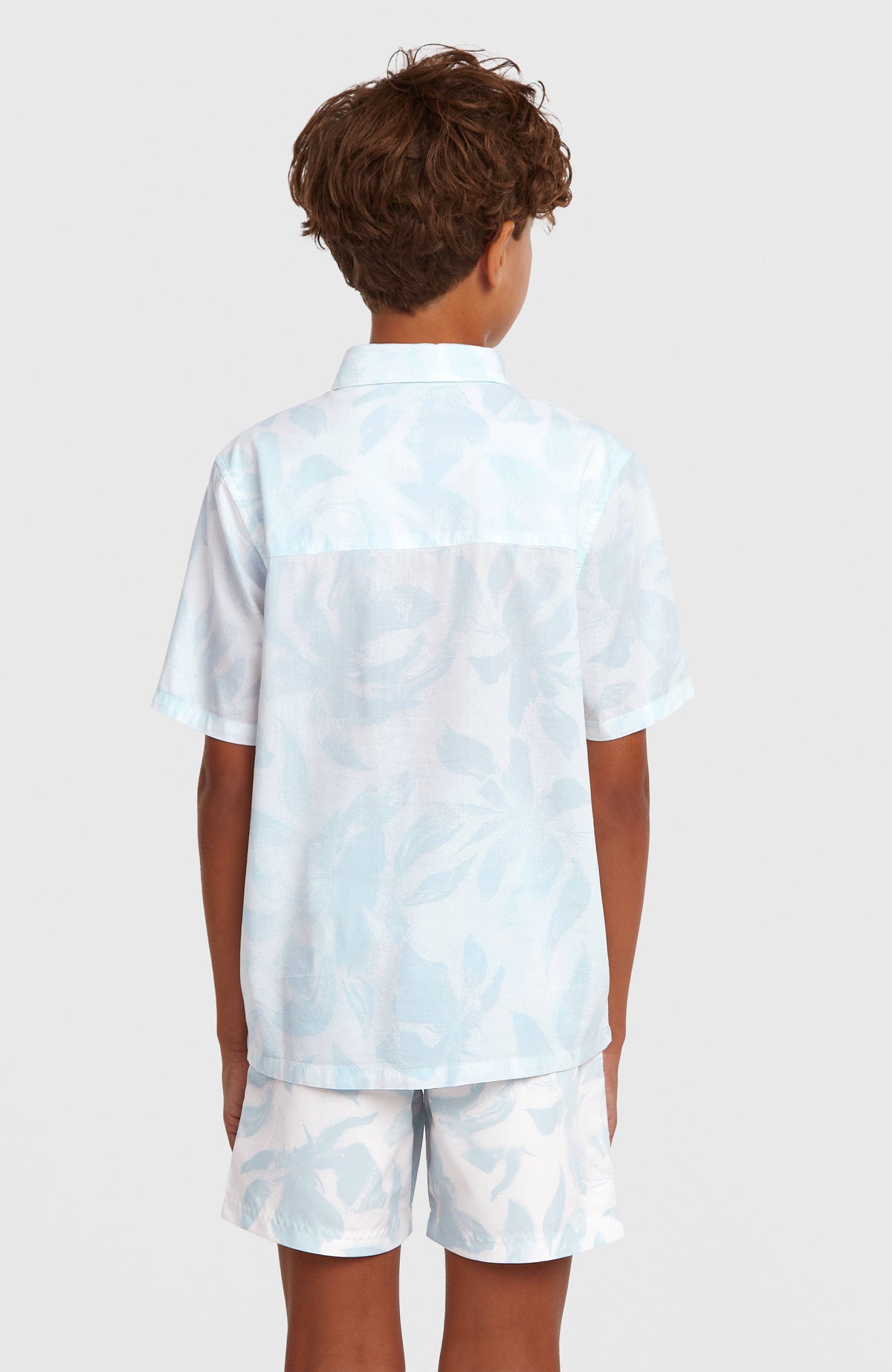 Print Badehose für Jungen, weiß mit Blumenmuster in Hellblau, Rückansicht am Model im abgestimmten Outfit