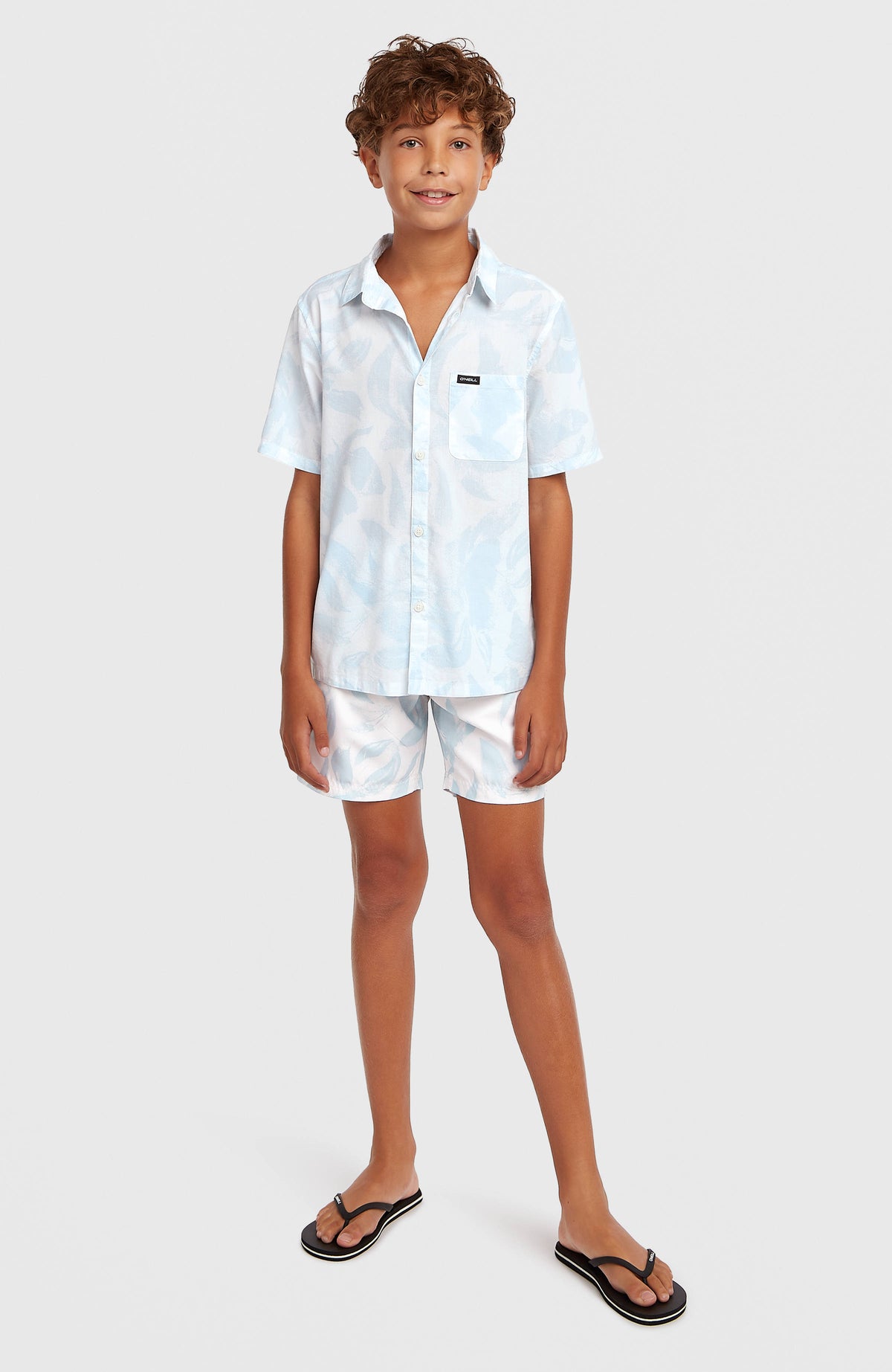 Print Badehose für Jungen, weiß mit Blumenmuster in Hellblau, Ganzkörperansicht am Model von vorne