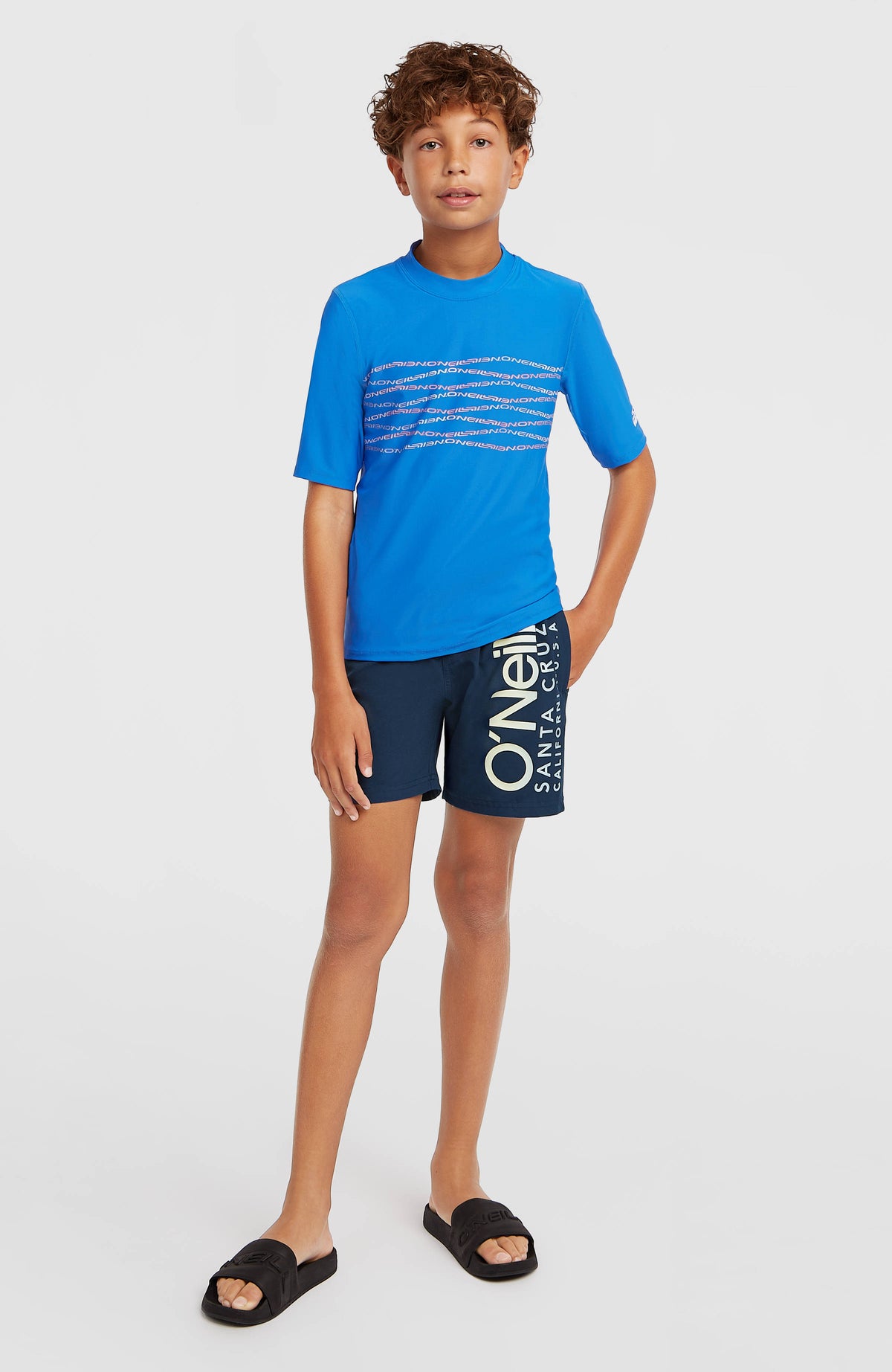 Blaue Cali Badehose für Jungen mit Logo-Print in Cremeweiß, Ganzkörperansicht am Model