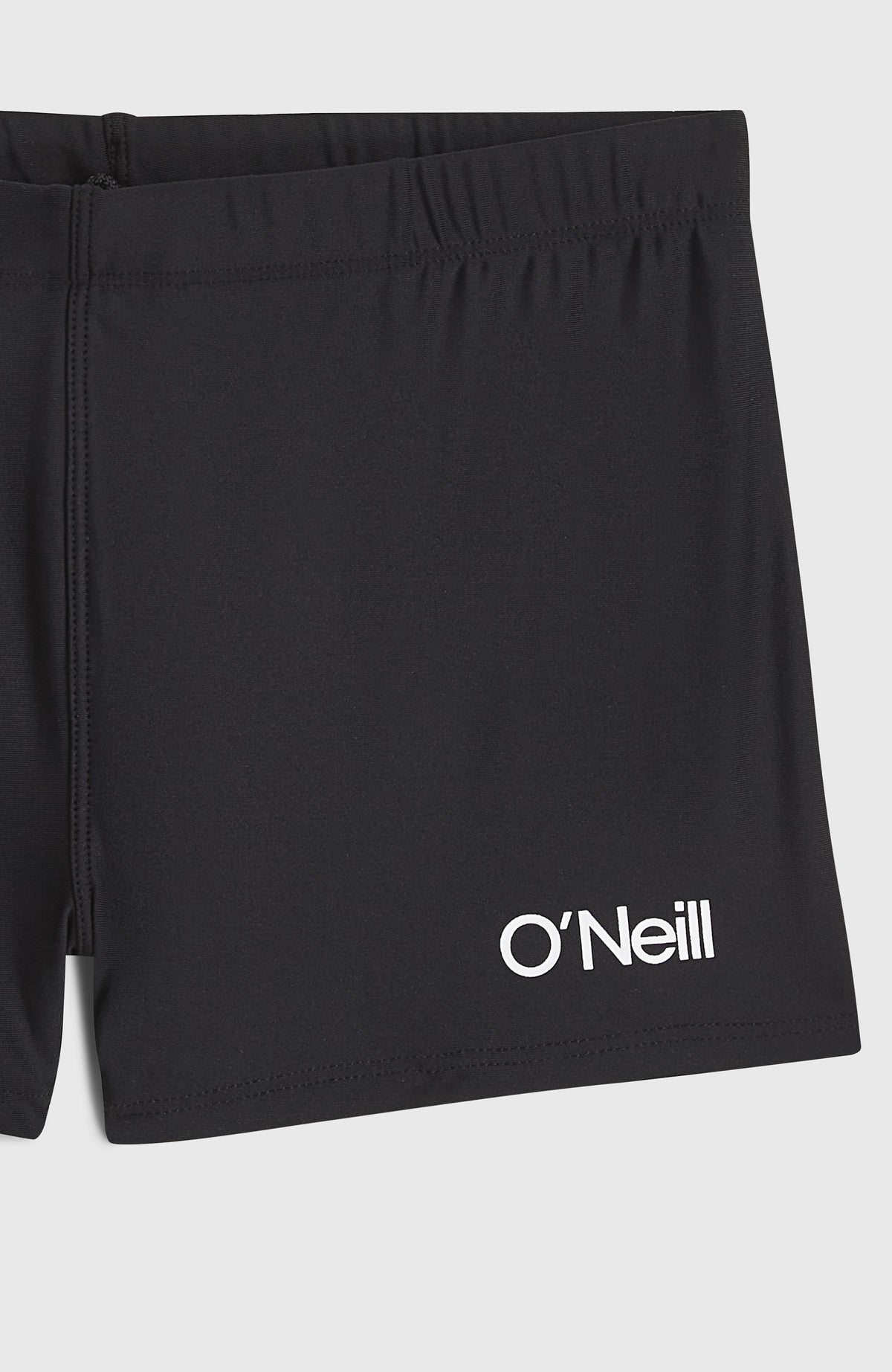 Nahaufnahme der schwarzen Racer Badehose, flach liegend mit weißem Logo-Schriftzug am Hosenbein