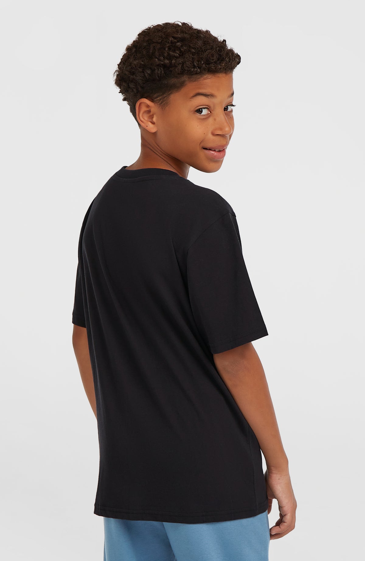 Must-Have T-Shirt für Jungen, schwarz, Rückansicht getragen am Model mit unifarbener Rückenpartie und kurzen Ärmeln
