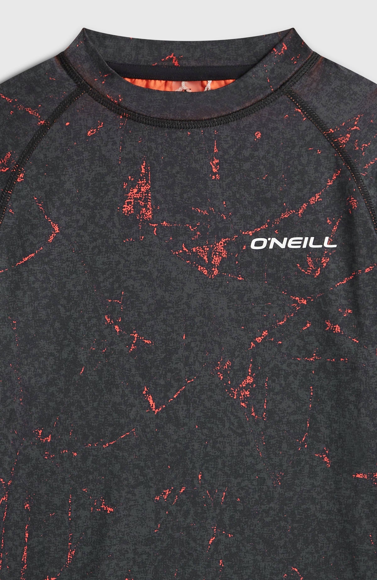 Nahaufnahme des Rundhalsausschnitts vom schwarzen Baselayer-Set mit Sprenkelmuster in Rot und Logo-Print