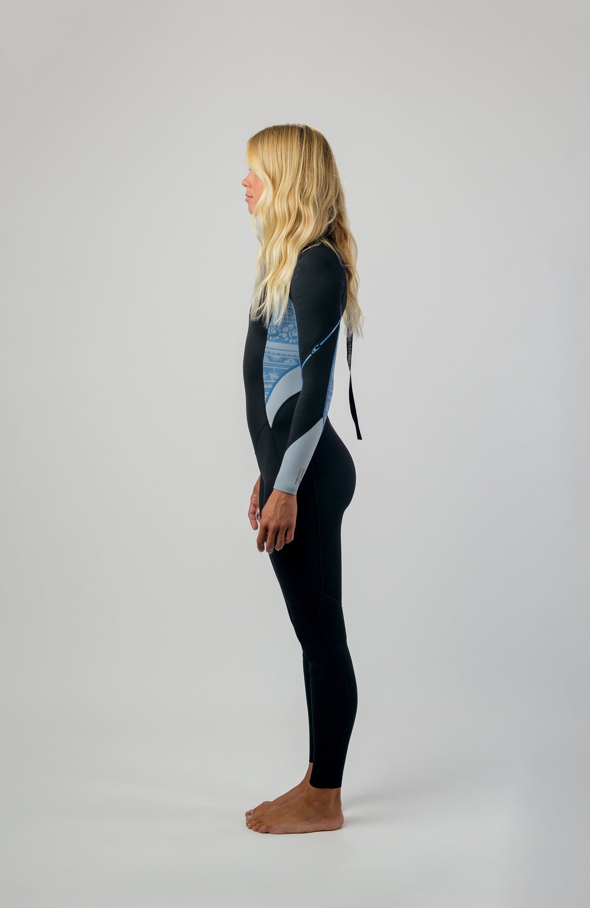 Wms Bahia 3/2 Back Zip Full Neoprenanzug für Damen, schwarz mit Surfmuster in Hellblau, getragen am Model in Seitenansicht