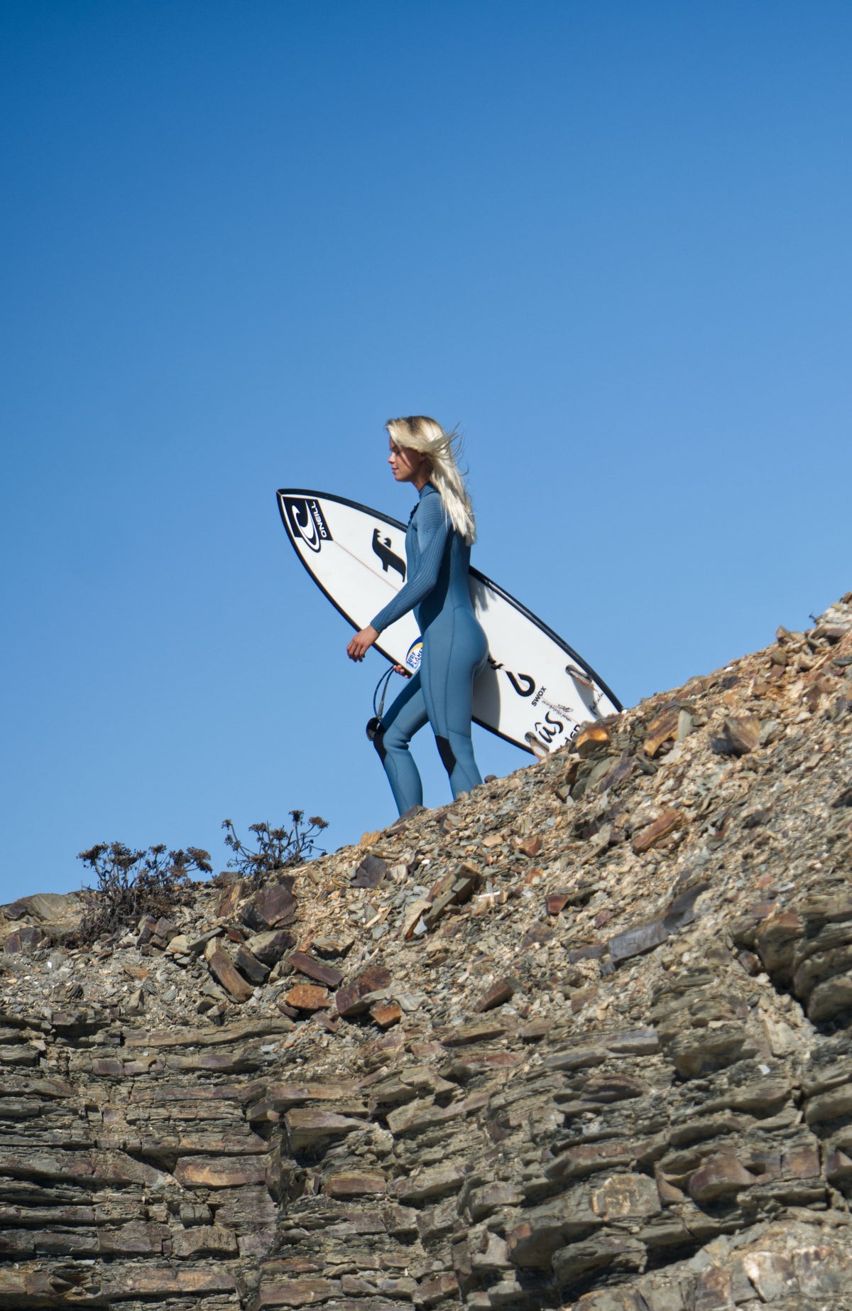 Hyperfreak Plus Neoprenanzug für Damen, blau, Ganzkörperansicht getragen am Model auf Felsen an der Küste