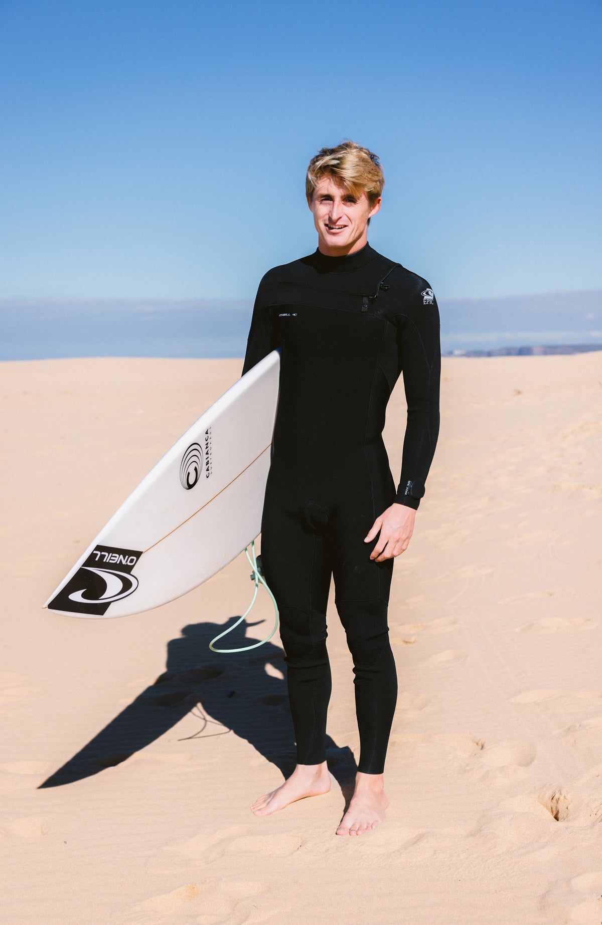 Epic 5/4mm Chest Zip Full Wetsuit Neoprenanzug für Herren, schwarz, am Strand, getragen am Model von vorne