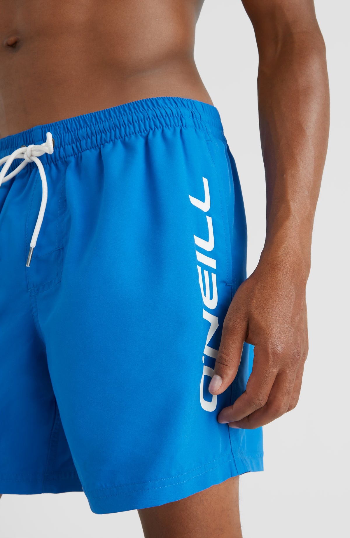 Cali 16'' Badehose, blau mit Logo-Print in Weiß, Nahaufnahme am Model mit Fokus auf den Bund