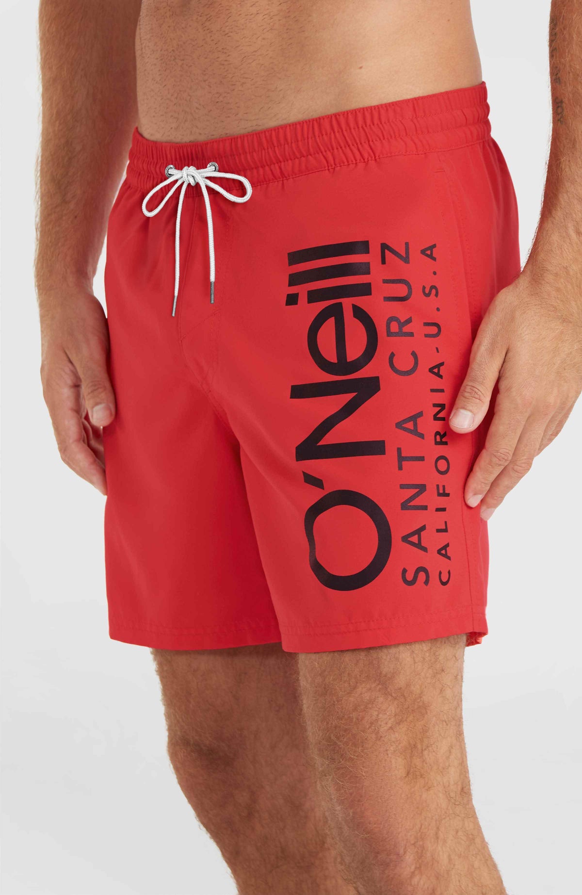 Nahaufnahme der roten Original Cali 16'' Badehose am Model mit großem Logo-Print und weißem Kordelzug