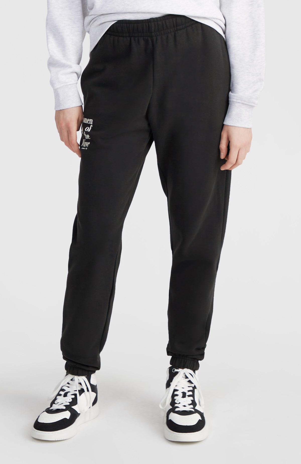 Women of the Wave Jogginghose, schwarz mit Logo-Print in Weiß, Vorderansicht am Model mit elastischem Bund