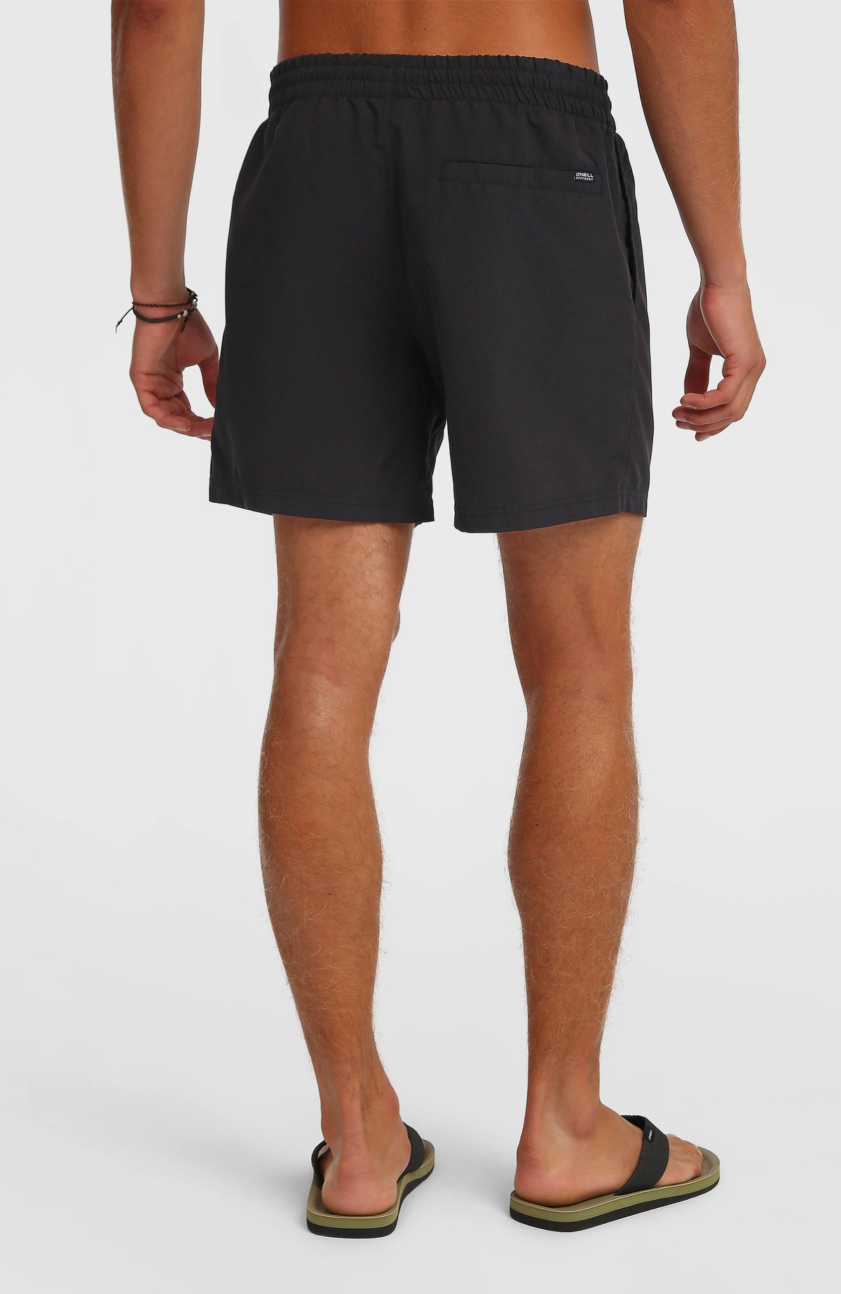 Schwarze Logo 16" Badehose für Herren mit Logo-Print in Weiß, Rückansicht am Model mit Tasche an der Rückseite