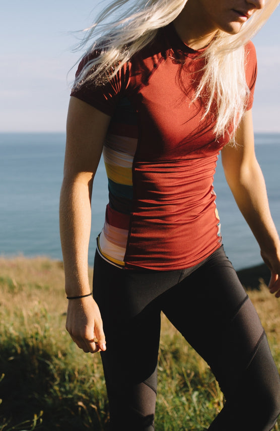 O'Neill Side Print Short Sleeve Rash Guard Schwimmshirt für Damen, rot mit Streifenmuster, am Model am Meer